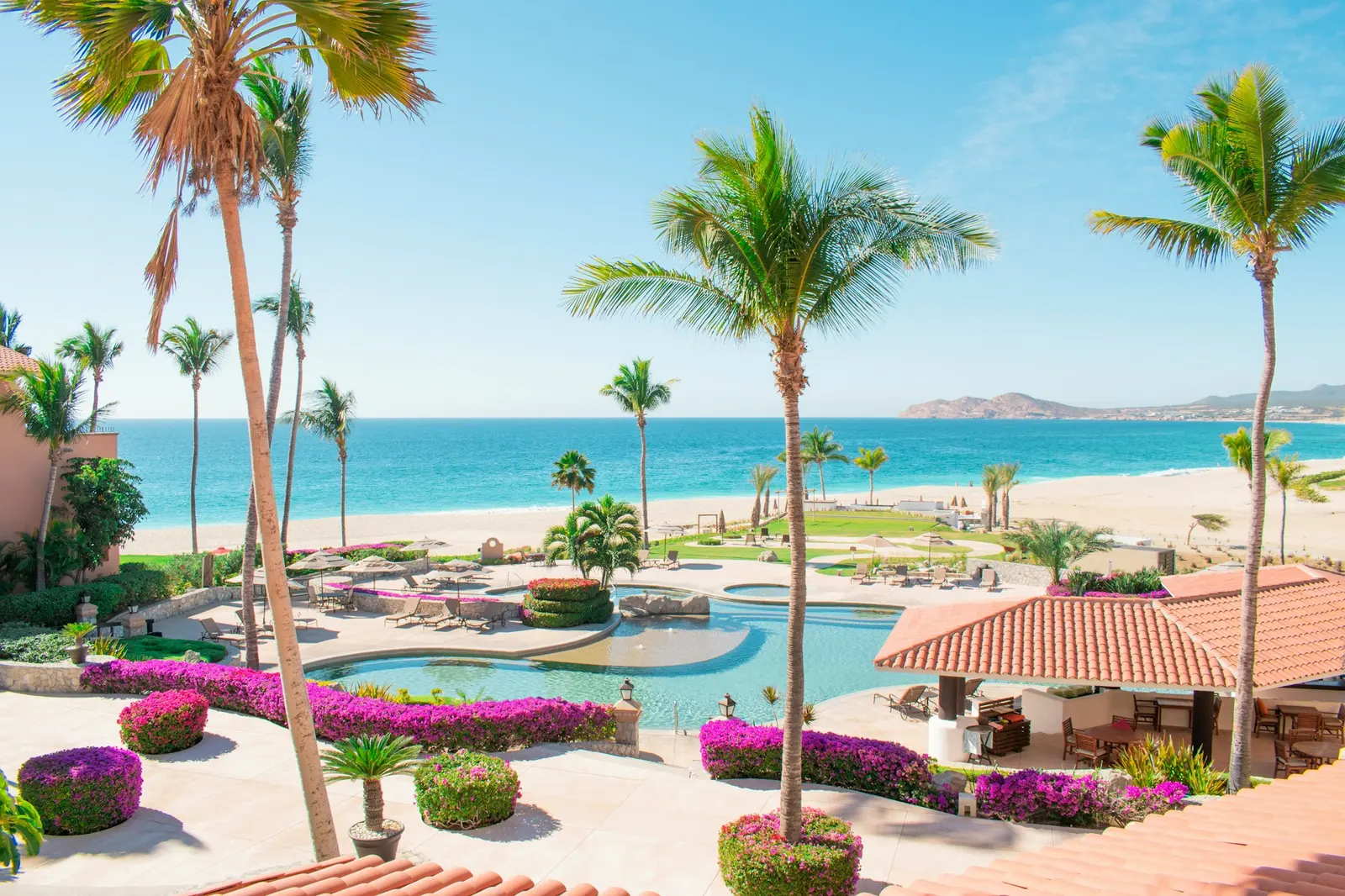 Wooden loungers beside a pool that looks out over the sea in Cabo San Lucas
